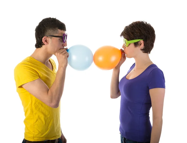 Man and woman with sunglasses blowing balloons — Stock Photo, Image
