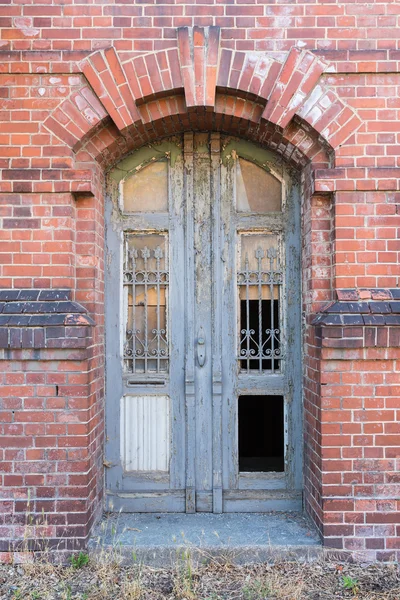 Antigua puerta en ruinas en la fachada de la casa de mampostería — Foto de Stock