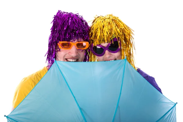Trendy couple with sunglasses and wigs protected by an umbrella — Stock Photo, Image