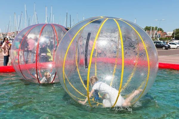 Children have fun inside plastic balloons on the water during a fishing fare — Stock Photo, Image