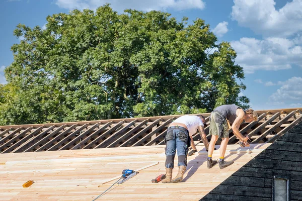 Twee bouwers bezig met het repareren van dak van houten schuur — Stockfoto