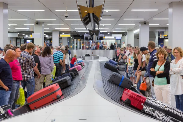 Viajantes de avião esperando por sua bagagem no aeroporto de Schiphol em Amsterdã, Holanda — Fotografia de Stock