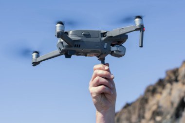 Man Hand launching a drone against blue sky