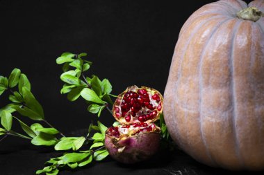 balkabağı ve kırmızı nar ve yeşil yapraklı tohumlar ahşap kesme tahtası, yan görüş, koyu arkaplan 