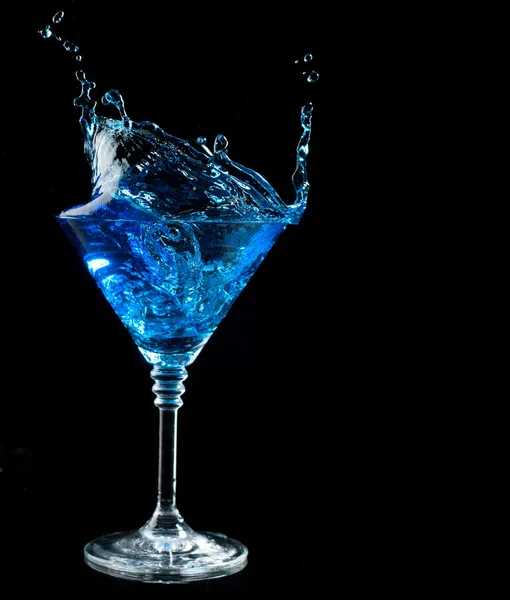 Blue cocktail splashing into glass on black — Stock Photo, Image