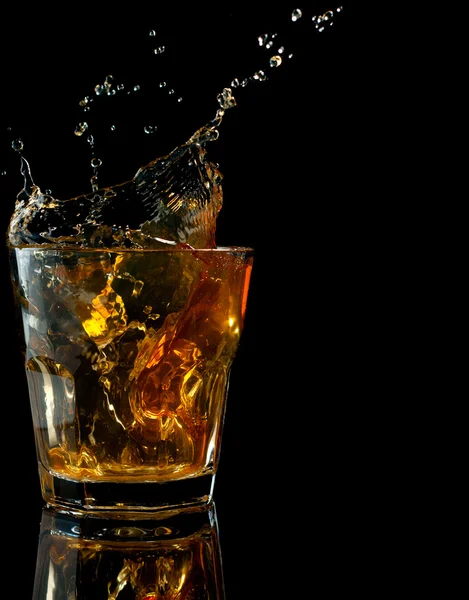 Glass of whiskey with splash, isolated on black — Stock Photo, Image