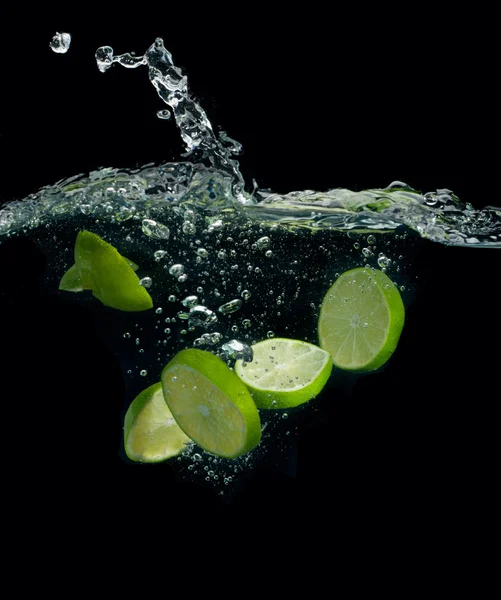 The lime slices falling into water — Stock Photo, Image
