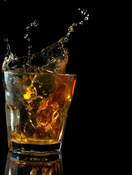 Glass of whiskey with splash, isolated on black — Stock Photo, Image