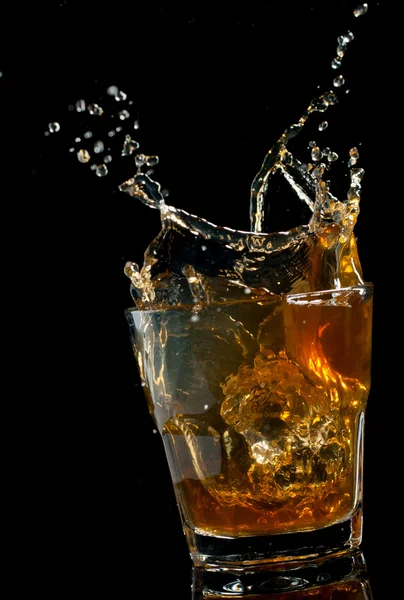 Glass of whiskey with splash, isolated on black — Stock Photo, Image