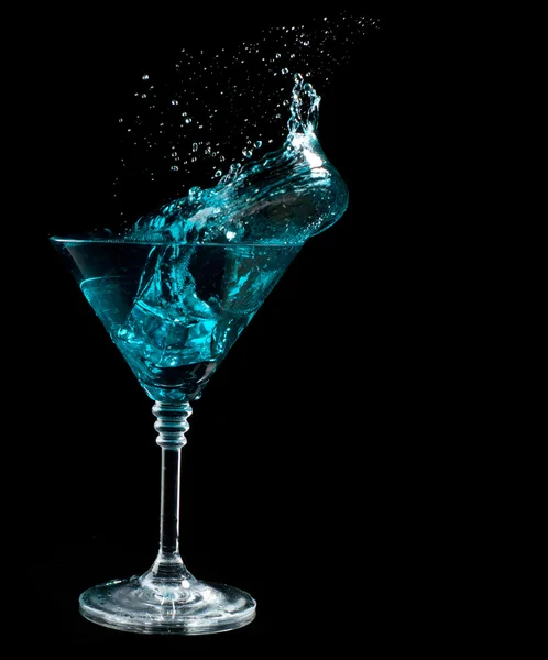 Blue cocktail splashing into glass on black — Stock Photo, Image