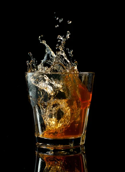 スプラッシュ、黒に分離されたウィスキーのグラス — ストック写真