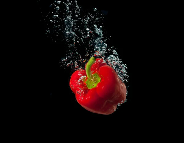 Spruzzata di pepe fresco in acqua su sfondo nero — Foto Stock