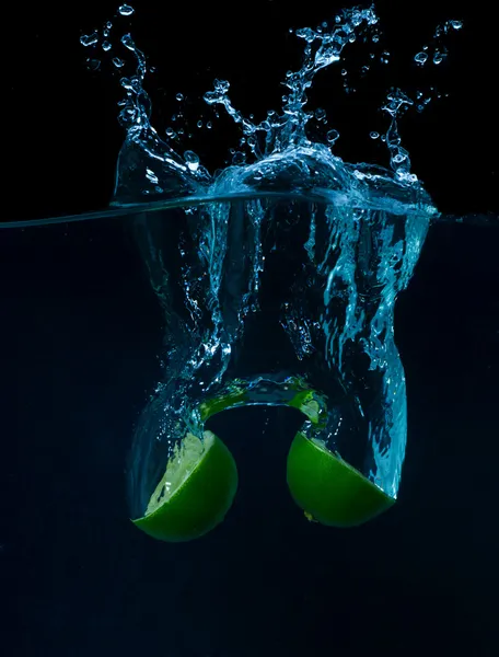 The lime slices falling into the water . — Stock Fotó