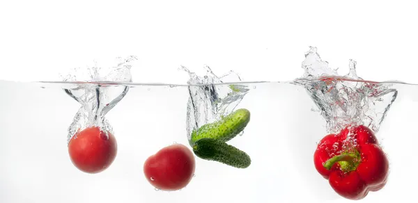 Cetrioli e pomodoro maturo cade profondamente sotto l'acqua con un grande splash. — Foto Stock