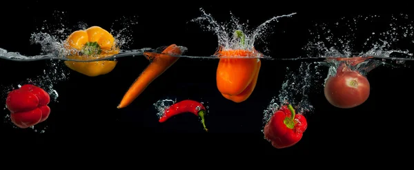 Verduras en el splash de agua sobre fondo negro. alimentación saludable y vida activa. — Foto de Stock