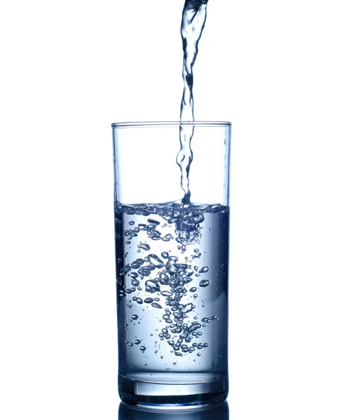 Agua que vierte en vidrio aislado en blanco — Foto de Stock