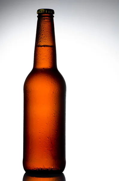 Бутылка пива с каплями воды на белом — стоковое фото
