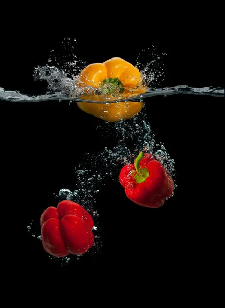 Färsk gul och röd paprika plaska i vatten — Stockfoto