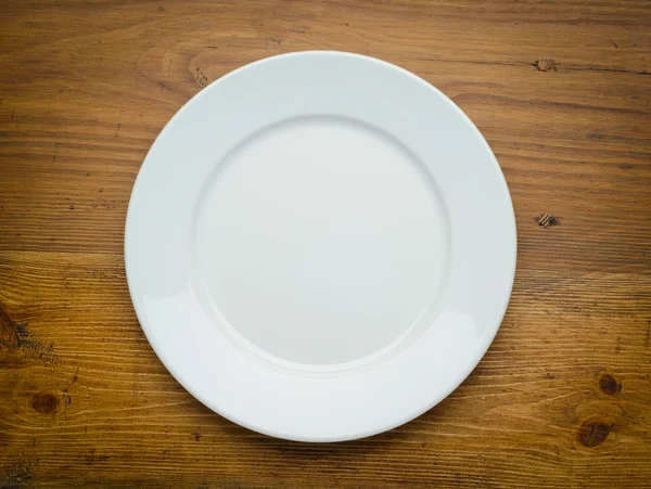 Pusty biały talerz na drewnianym stole — Zdjęcie stockowe