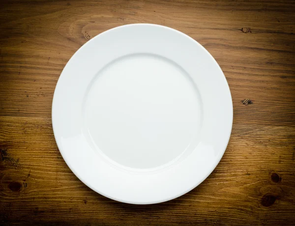 Пустая белая тарелка на деревянном столе — стоковое фото