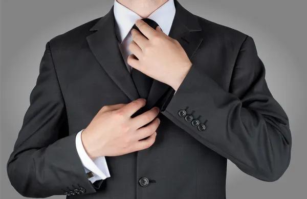 Empresário em traje preto amarrar um 's necktie — Fotografia de Stock