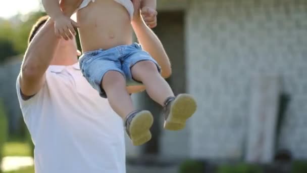Szczęśliwy chłopiec z zespołem Downa bawi się z ojcem na ulicy. Ojciec rzuca dziecko w jego ramiona — Wideo stockowe