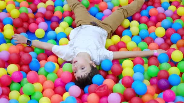 Boy falling down into pool with colored balls, autism spectrum disorder — Stock Video