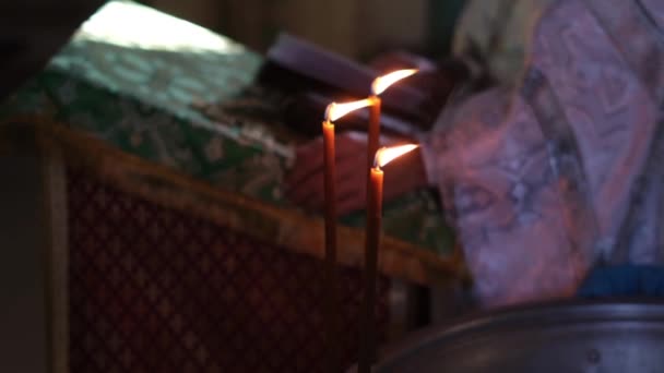 Een priester in een soutane leest de Bijbel. De priester bidt terwijl hij in de kerk staat. Een orthodoxe priester houdt een gebed ceremonie. — Stockvideo