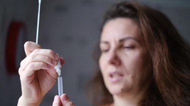 Genç bir kadın evinde Covid-19 antijeni için kendini test ediyor.