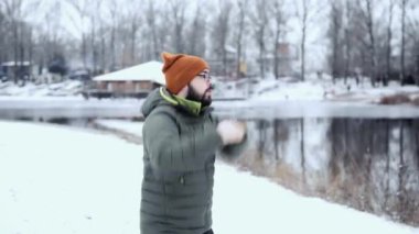 Kışın göl kenarında bir sporcunun eğitimi. Trail runner, soğuk havada egzersiz yapan sağlıklı bir insan. Adam egzersizlerini yapıyor. Sporcu kış ormanlarında egzersiz yapar..