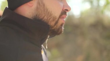 Adam koşuyor, parkta egzersiz yapıyor. Yüzü yakın plan. Sağlıklı yaşam tarzı, açık hava sporları. Yavaş çekim