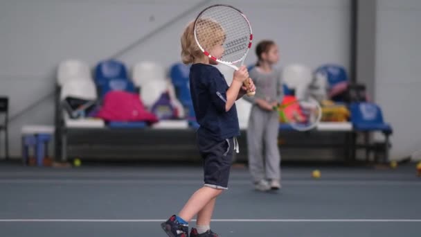 Chłopiec trening gry w tenisa na krytym korcie. — Wideo stockowe