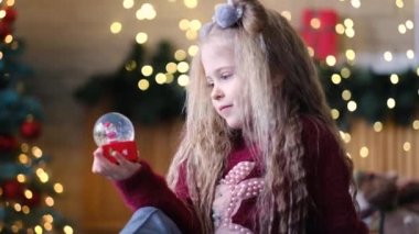 Kız elinde karla cam bir top şeklinde bir hatıra tutuyor ve onu sallıyor. Noel 'den ve Yeni Yıl' dan önce neşeli bir atmosfer