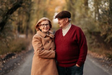 Kıdemli evli çift sonbahar parkında dans ediyor, yıldönümlerini kutluyor, sevişiyorlar. Mutlu yaşlılar.