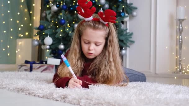 Menina em um clima festivo escreve uma carta ao Papai Noel — Vídeo de Stock