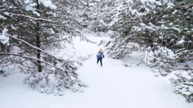 Karlı bir kış parkında bir çocuk oynuyor. Peri buz ormanında küçük bir çocuk. Kış ormanında yürü. Olumlu, gerçekten parlak duyguların ifadesi, gülümse..