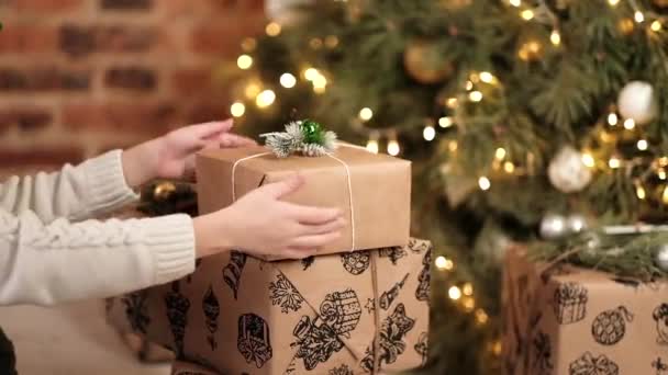A curious boy takes Christmas presents from under the tree, shakes it, tries to find out whats inside. Happy christmas for baby — Vídeo de Stock