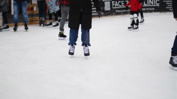 Крупный план фигурного катания. Ледовый каток зимой. Люди катаются на коньках. Коньки ездят по льду. Катание на коньках - это зимний спорт и развлечения. Женщины, дети, мужские ноги. Время Рождества. — стоковое видео