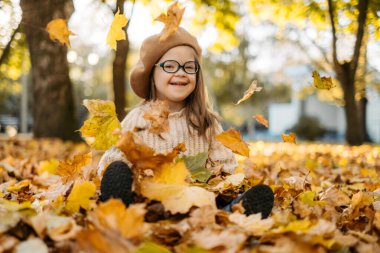 Engelli mutlu çocuk sonbahar günlerinde parkta eğleniyor sonbahar yapraklarını atıyor