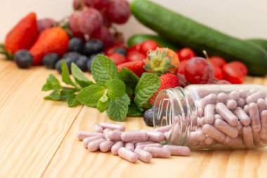 Canberry multivitamin and mutimineral capsuls,  nutritional  supplement  in glass bottle on wooden table with variety fruit