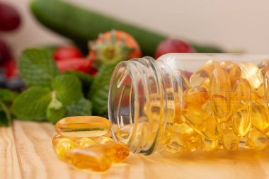 Fish oil, omega 3 with vitamin Dcapsules in the glass bottle on wooden table with variety fruits.