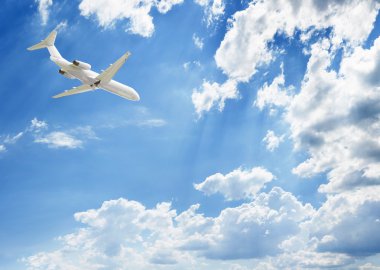 Mavi bulutların üzerinde uçan bir uçak