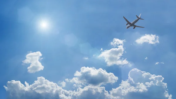 Самолет, летящий над голубыми облаками — стоковое фото