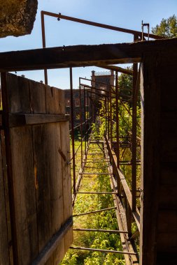 Terk edilmiş bir hidroelektrik santralindeki binalar arasında geçiş, değirmen, demir geçidi, tesisat, eski terk edilmiş fabrika.