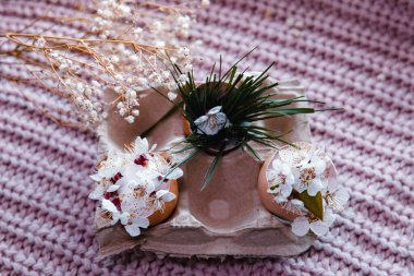egg with a bow on a textile pink background with white dried flowers and white blooms