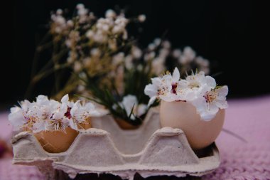 egg with a bow on a textile pink background with white dried flowers and white blooms