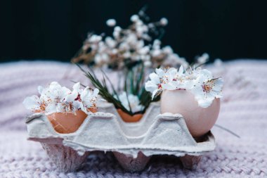 egg with a bow on a textile pink background with white dried flowers and white blooms