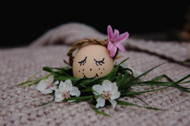 egg with a bow on a textile pink background with white dried flowers and white blooms