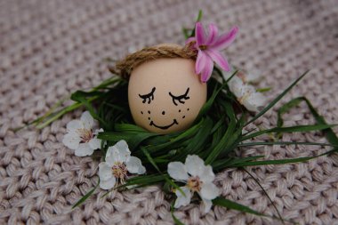egg with a bow on a textile pink background with white dried flowers and white blooms