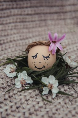 egg with a bow on a textile pink background with white dried flowers and white blooms
